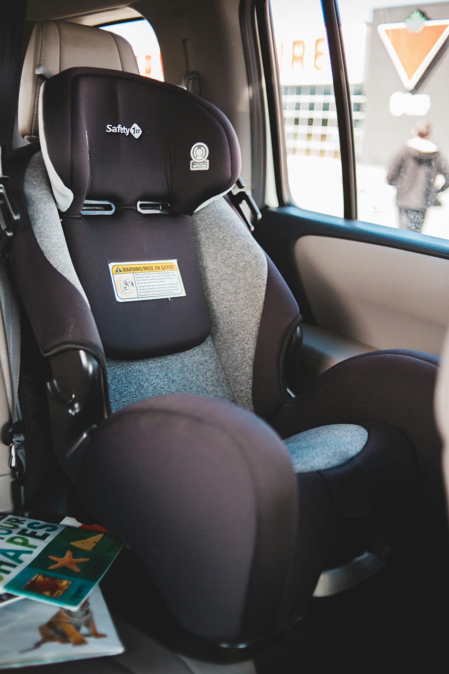 Child car seat installed in the back seat of a compact car with a children's book on the seat